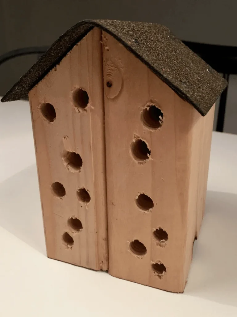 Hemmagjort insektshotell i trä och tak i tjärpapp.